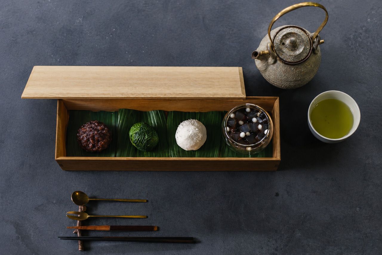 Drei Sorten traditioneller japanischer Süßigkeiten von SISIRI, ein kleines Anmitsu (ein Dessert mit roter Bohnenpaste und Früchten) und ein Getränk.